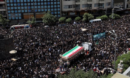 Aerial view of the flag-draped coffin being driven through dense crowds