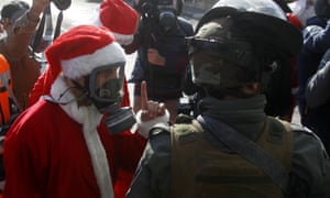 A Palestinian protester dress up like Santa Claus argues with Israeli security forces at the separation wall in Bethlehem.