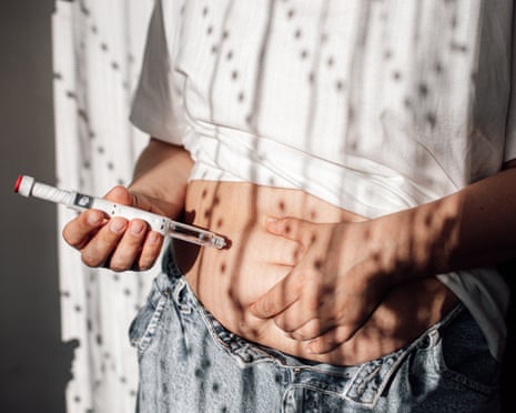 A woman injects herself with a GLP-1 weight-loss drug.