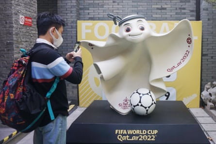 A man takes a picture of the HRWC mascot outside a store in Hangzhou, China
