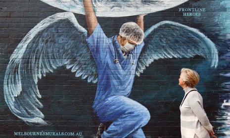 A woman looks at a mural of a health worker