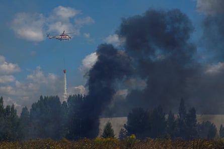 A firefighting helicopter drops water over a food warehouse damaged during Russian drone strikes near Kyiv, 12 August 2026.