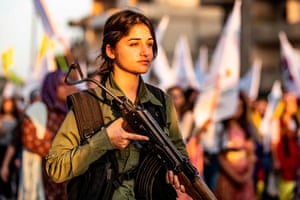 Um oficial de segurança curda fica de guarda em um comício contra ameaças turcas de invadir a região em Qamishli em agosto.