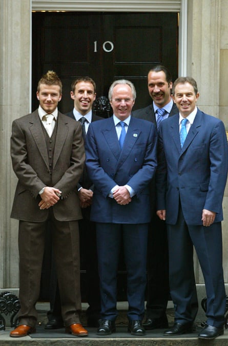 David Beckham, Gareth Southgate, Sven Göran Eriksson, David Seaman and Tony Blair, all wearing suits and ties and standing on the steps of 10 Downing Street