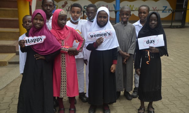 Young girls hold signs saying 'happy women's day' 