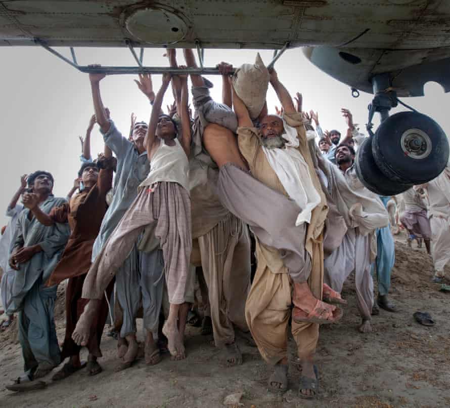 Marooned flood victims looking to escape grab the side bars of a hovering Army helicopter which arrived to distribute food supplies in the Muzaffargarh district of Pakistan’s Punjab province. The disaster killed more than 1,600 people and disrupted the lives of 12 million. 7 August, 2010