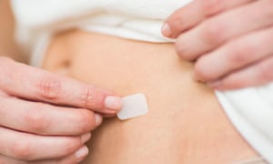 A woman applies an HRT patch