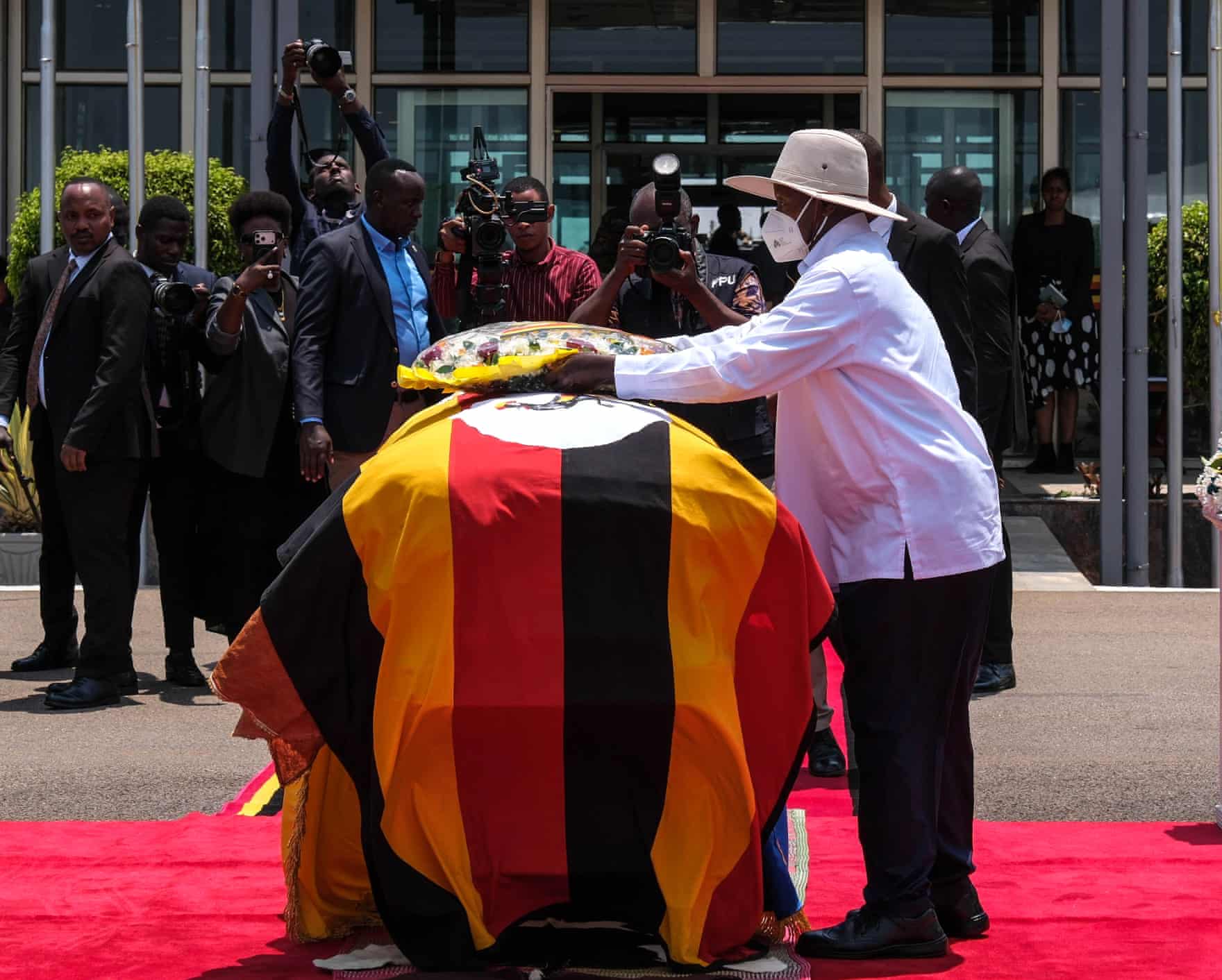 Uganda’s president, Yoweri Museveni, lays a wreath on a casket covered by the Ugandan flag