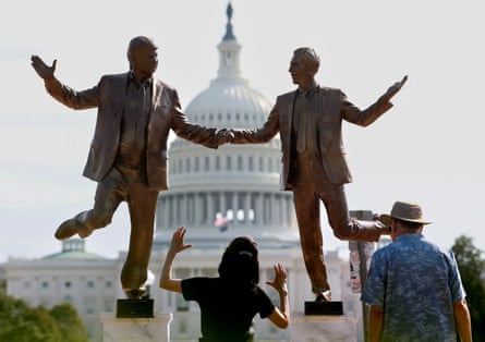 Visitors look up at a pop-up statue depicting Donald Trump and Jeffrey Epstein.