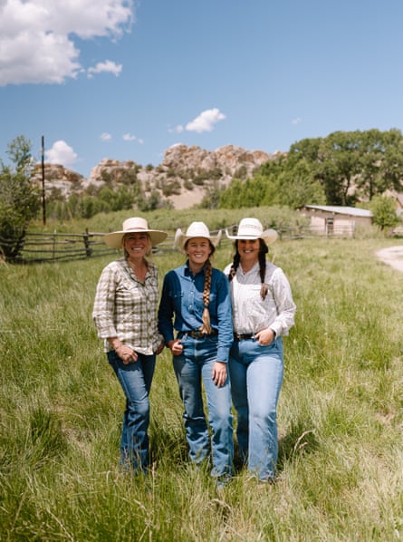 three women in cowgirl hats smile on a ranch