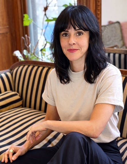 A woman with dark hair sits on a couch in a home