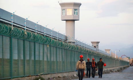 Workers walk by the perimeter fence of what is officially known as a vocational skills education centre in Dabancheng, Xinjiang, China.