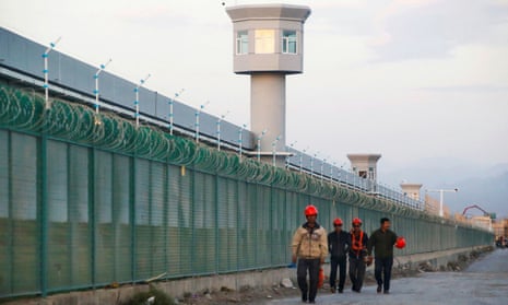 Workers walk by the perimeter fence of what is officially known as a Uighur ‘vocational skills education centre’ in Dabancheng, Xinjiang, China.