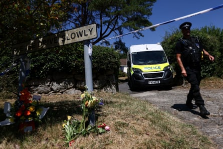 A police officer walks past floral tributes left outside the home of Ann Widdecombe.