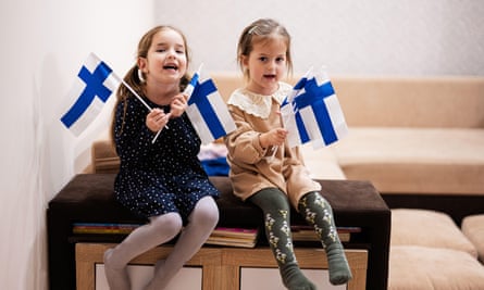 Two girls holding Finnish flags smiling