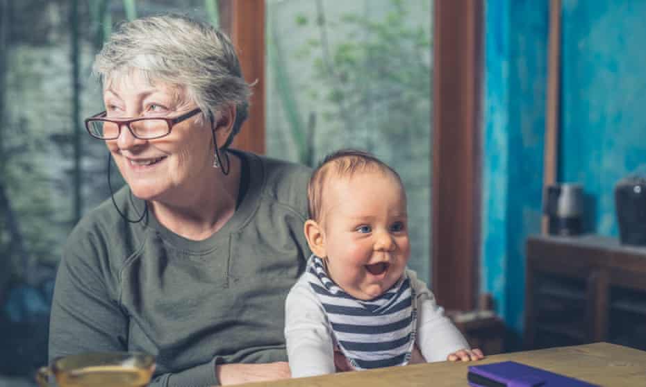 A grandmother is sitting at a dining table with her baby grandchild.