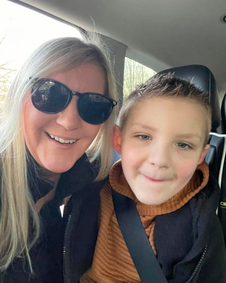 A woman smiles next to child wearing seatbelt
