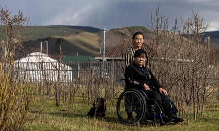 A Mongolian mother with her daughter in a wheelchair, with their ger in the background.