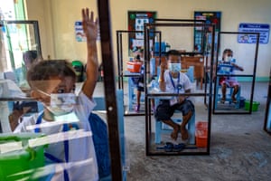 Elementary students sit inside dividers as a preventive measure against Covid-19, as they attend the first day of physical classes at Longos elementary school.