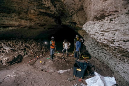 A large cave with a group of people digging in it.