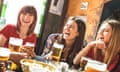 Happy group of young women drinking beer at a pub.