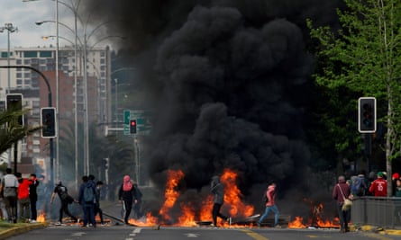 Demonstrators stand next to a burning barricade in Chile