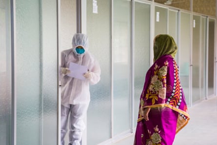 A woman with suspected coronavirus gives her data to a health worker in a white protective suit at a collection point
