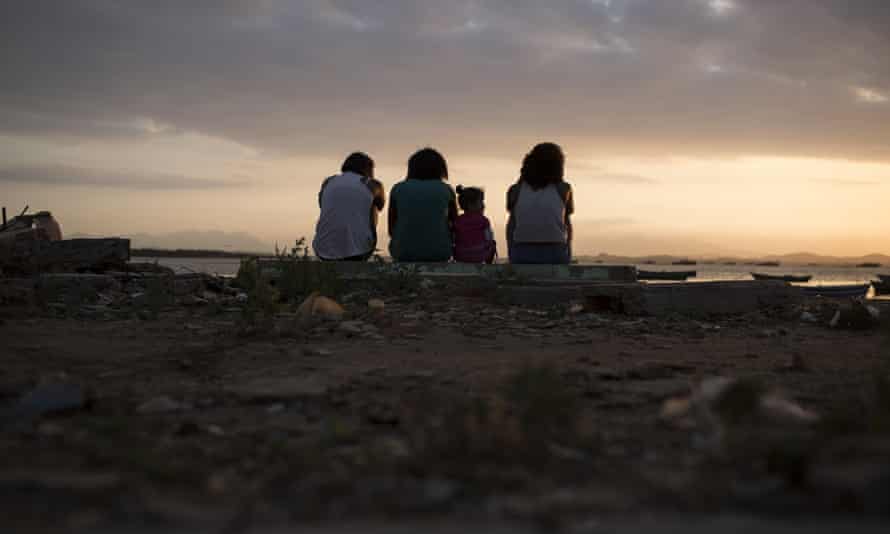 Girls sit near the shores of Guanabara Bay, the venue for sailing at Rio 2016.
