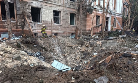 A rescuer stands next to a crater outside an apartment building left by a Russian missile strike in Mykolaiv