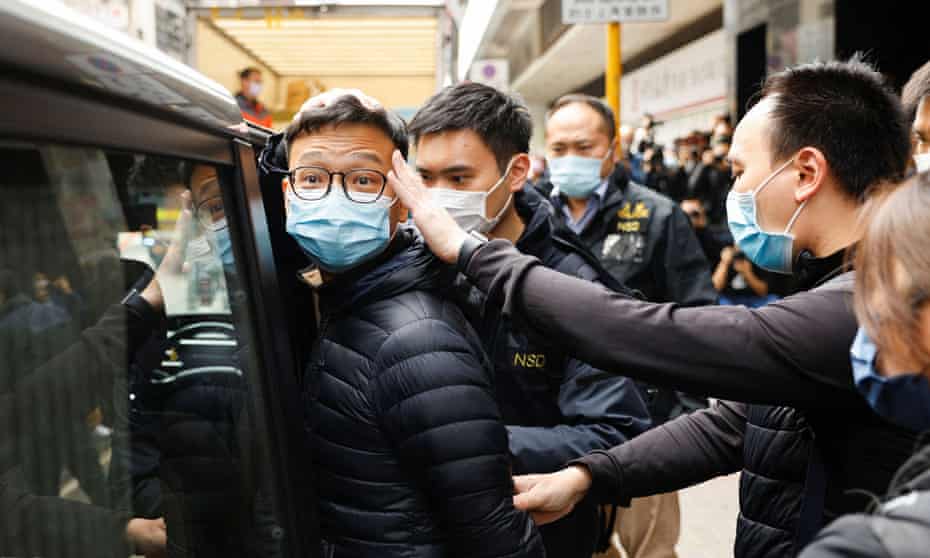 Stand News acting chief editor Patrick Lam is escorted by police as they leave after the police searched his office in Hong Kong on 29 December 2021.
