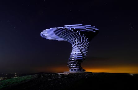 The Singing Ringing Tree sculpture glows blue under a starry sky
