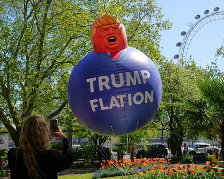 A passerby takes a picture of a balloon in the caricature of US President Donald Trump as Britain’s Liberal Democrat party launch their new “Trumpflation” campaign as latest inflation figures reveal the impact of the Iran War on prices in the UK