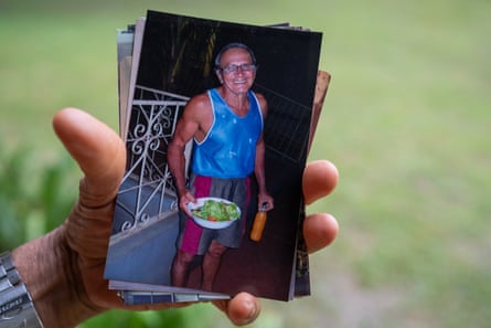 A hand holds a photograph of a man smiling and holding a bowl of salad and a bottle of juice.