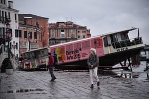 People walk past a stranded taxi boat on Riva degli Schiavoni