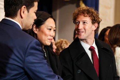 a man smiles and speaks with another man as woman in between them looks forward