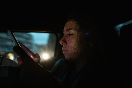 Nihal looks at her phone inside a car