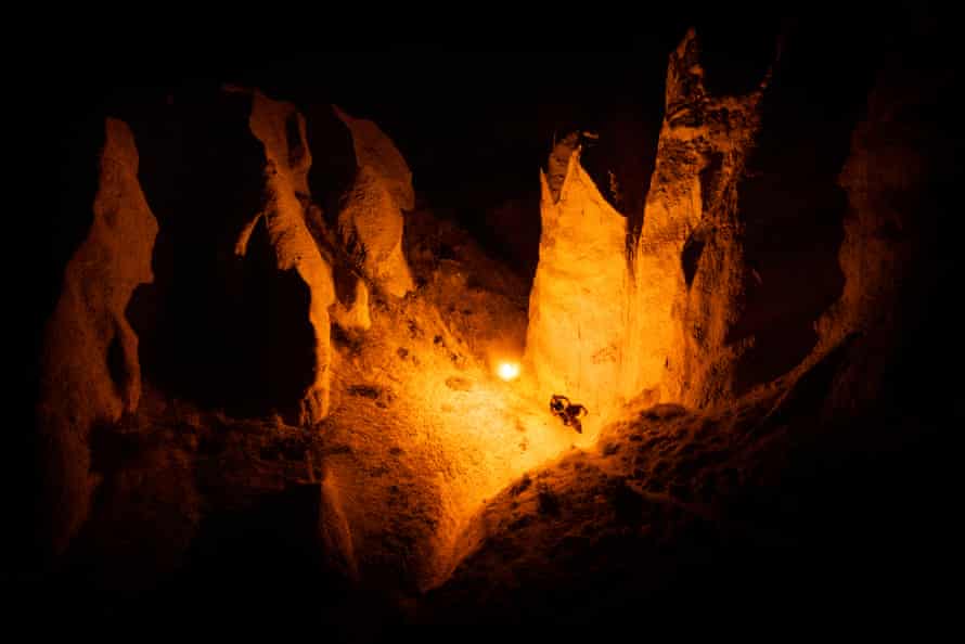 Bron lit by a flare mounted on a drone through a narrow canyon at night