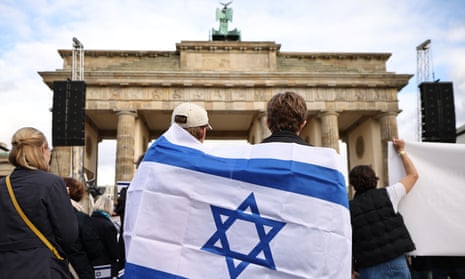 Israel-Hamas war live: White House promises ‘continued flow’ of Gaza aid as Israel steps up airstrikes in north of strip | Israel-Hamas war 5 Demonstrators wrap an Israeli flag around their shoulders in front of the Brandenburg Gate.