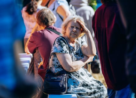 A woman sits among other people near the site of the attack on Solomyanskiy district