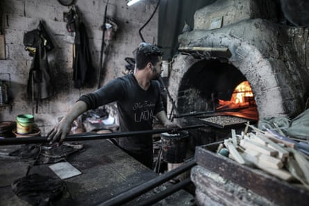 A baker putting a dish into a bakery oven