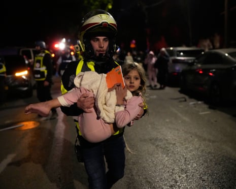 An Israeli rescuer carries a child after a missile attack from Iran hit in Tel Aviv.