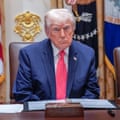 Donald Trump in suit sitting at table with folder open in front of him