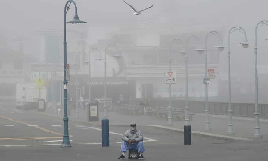 A street performer sits alone at Fisherman’s Wharf in San Francisco, 12 March 2020. Coronavirus cases in California are growing.