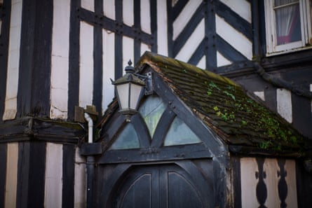 A moss-covered gabled porch roof with a lantern over a dark wooden door at the Four Crosses pub in Cannock