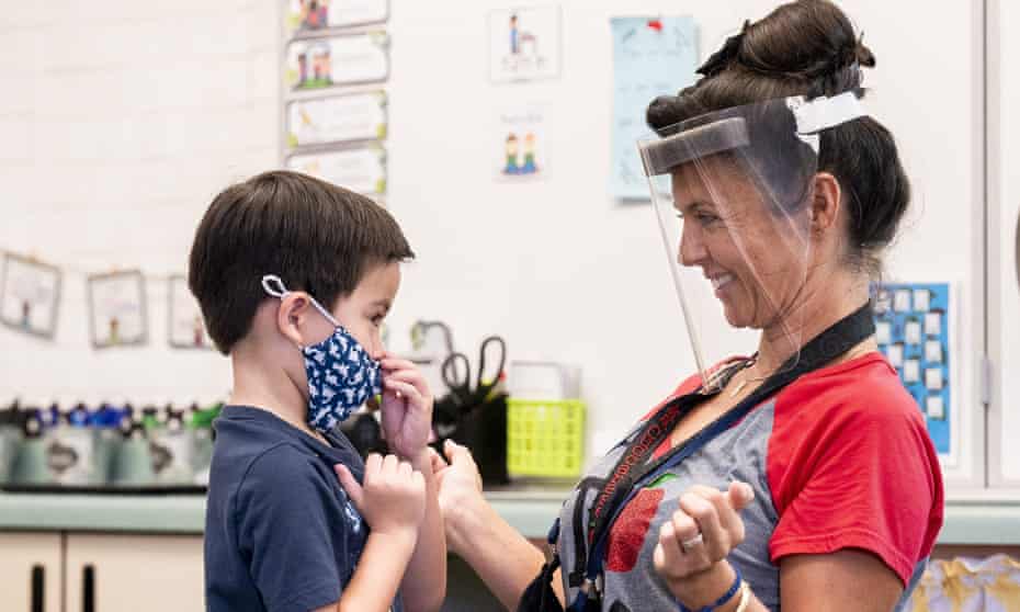 Annette Cuccarese, a kindergarten teacher at Tustin Ranch Elementary School in Tustin, California, helps a student with his mask. Many schools faced teacher shortages this year. 