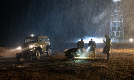 Nightime. Military vehicle off the side of the road. Men holding torching looking at something on ground in rain