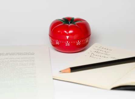 A tomato-shaped cooking timer next to a note pad