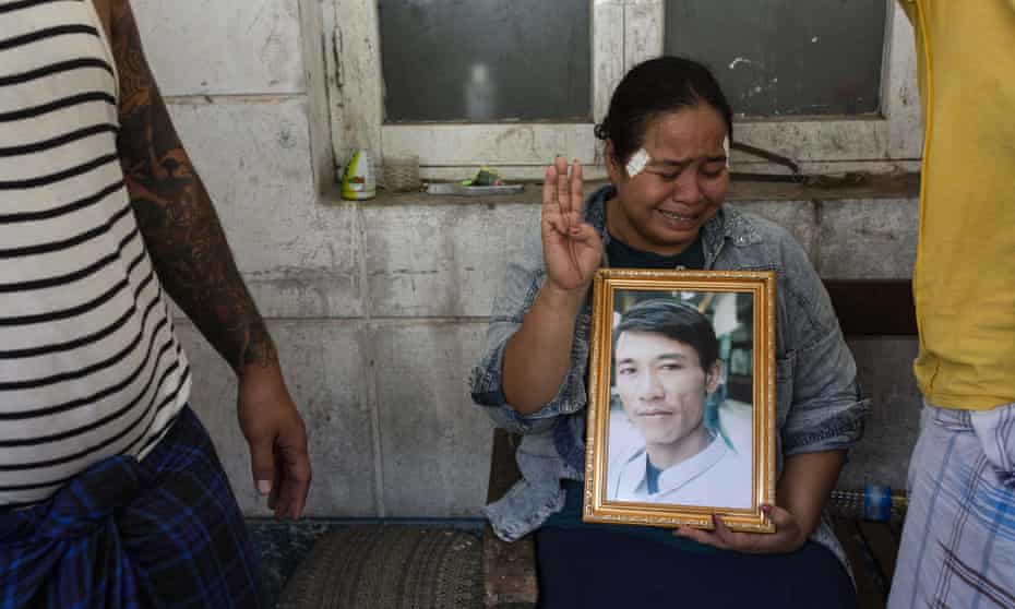 A woman in tears makes the three finger salute while holding a portrait of her relative shot dead a day earlier by security forces