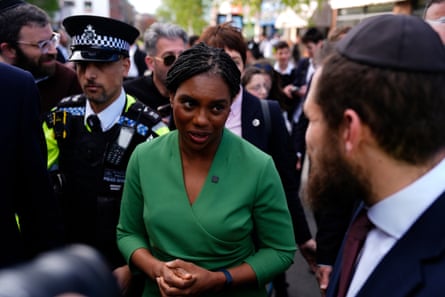 Kemi Badenoch talks to a man wearing a yarmulke as she walks through Golders Green with a police escort