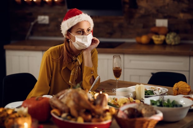 It wasn’t a Christmas dinner as it used to be!Pensive woman wearing face mask and sitting alone at dining table on Christmas eve.